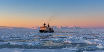 US Coast Guard icebreaker in a vast, icy Arctic landscape at sunrise, symbolizing American strategic presence.